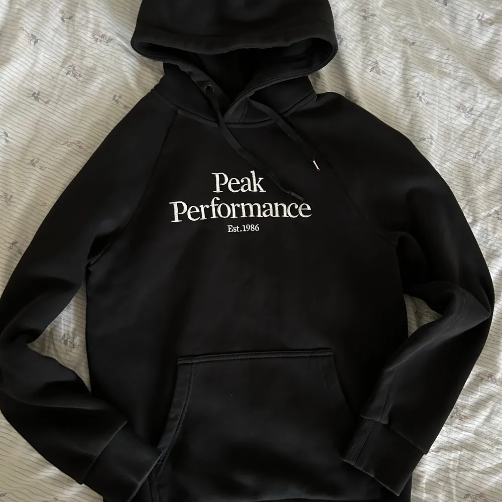 En svart PeakPerformance hoodie i mycket bra skick. Storlek S. Var uppmärksam på att ena hylsan på snöret är borta. Säljer då jag inte har fått användning av den. . Hoodies.