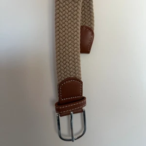 Flätat bälte  - Bältet är i mycket bra skick och helt oanvänt det är också riktigt snyggt. Färg på bältet är beiget.