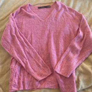 En rosa stickad tröja som är v-ringad. Storlek M, tröjan är köpt på veromoda.