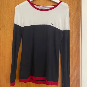 Tunn stickad Tommy hilfiger tröja - Supersnygg och skön! Köpt secondhand och pga mjukt material sitter den väldigt bra!🌟 Tyvärr lite fläckar på det vita partiet fram vilket syns på andra bilden men som troligen går bort i tvätten 🌟 Skriv för fler bilder eller frågor 🌟