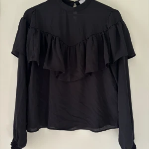 Blus  - Storlek: S Svart elegant blus med volanger 
