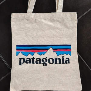 Helt NY Patagonia tygväska / shoppingpåse - Helt ny och oanvänd! Ca 36x31 cm, tryck på ena sidan. Avhämtning eller skickas mot fraktkostnad, köpare står för frakt. Priset är fast. 