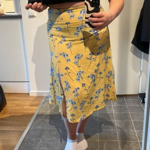 Gul blommig kjol - Kjol med dragkedja bak. Slits på ena benet.