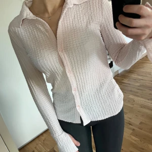 Ljusrosa skjorta - Säljer den här skitsnygga ”våfflade”, ljusrosa skjortan från Lindex. Långa ärmar med slitsdetalj så handen sticker fram. Använd en gång, säljer då jag tyvärr inte får användning för den.