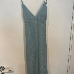 Glitter fest klänning - Säljer då jag använt 1 gång och är inget för mig. Kort fest klänning. Storlek S från H&M Divided. En liten slit vid ena sidan. Kors i ryggen och öppen rygg. Passar någon som har S och M skulle jag säga.  Den är Glittirg men inget som glittrar av sig.