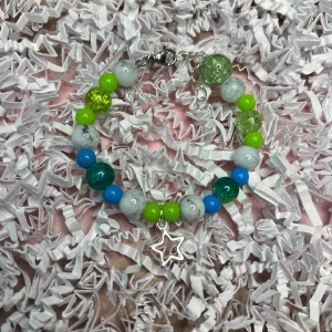 Grönt och blått armband med berlock  - Grönt och blått armband som går att justera.