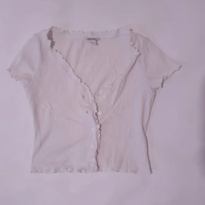 Vit t-shirt Monki  - Vit super fin t-shirt. Super romantiskt med dem små volanger där man knäpper den. I mycket bra skick 