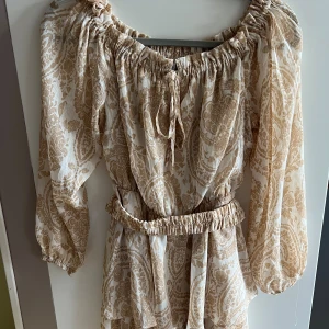 Beige off shoulder playsuit  - beige off shoulder playsuit från New Yorker med prislapp kvar. Avtagbart bälte i midjan strl 38