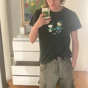 Dedicated T-Shirt Snobben och Charlie - Grön Dedicated T-Shirt med Print av Snobben och Charlie Brown  Fint skick