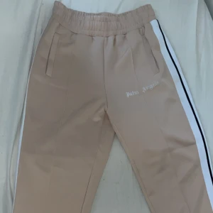 PALM ANGELS BYXOR - Säljer ett par beigea palm byxor i storlek M. Helt nya testat endast en gång, sälj pågrund av att de inte passade. Skick 10/10 hör gärna av dig om du är intresserad.