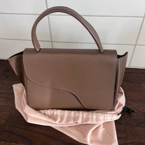 ATP atelier - Arezzo Khaki Brown Leather Handbag Nypris 4800kr  Mått: H 18,5cm B 34cm D 10,5cm. Crossbodyrem: 90,5cm. Crossbody remfall: 47cm. Topphandtagsfall: 9,5 cm.  Använd Max 6-8 gånger, den ”luktar” forfarande ny. Har en liten ”repa” på baksidan som kan fix