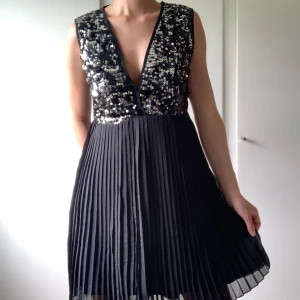 Svart klänning med silvriga paljetter - Dragkedja i ryggen.