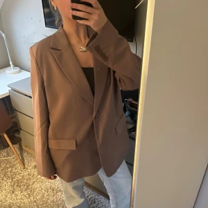 Blazer - Brun blazer från NA-KD, oanvänd. Köpt för ca 700 kronor. Säljer för 200 kronor. (Blazern är inte fläckig utan spegeln)