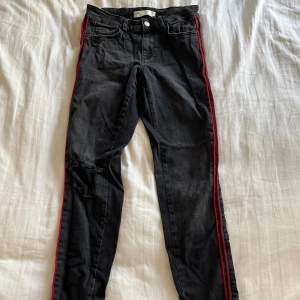 Svartgråa jeans med slitningar och två röda sträck på sidan ifrån Zara i storlek 36