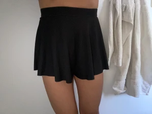 Korta shorts/ kjol - Svarta shorts i elastiskt tyg som en kjol. Storlek XS/ 34