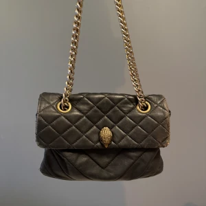 Kurt Geiger Väska - Svart kurt geiger väska med guld detaljer. Väl använd och därmed små slitningar på sidan, som syns på bild 1, annars i bra skick💗