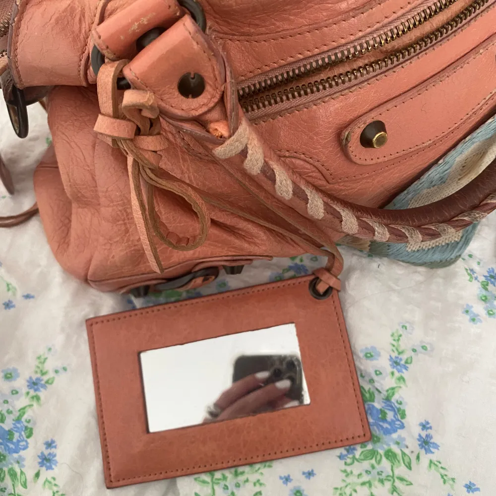 Model: balenciaga city bag Pink leather, the mirror, authenticity card from collectorscage comes along, and also the receipt if wished. The bag strap does not come along.   Ver good condition, only small worn-signs as showed in pictures . Accessoarer.
