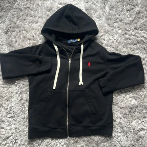 Polo Ralph Lauren Zip-Tröja Svart/Röd Tracksuit Hoodie Storlek M  - Säljer denna tvärfeta ralph lauren som ja köpte av min kusin , har bara inte använt den så mycket så bättre att nån annan tar den! En av drawstringsen e typ upprivd elle något så biligare pris pga de. Skickar samma dag innan kl 22 me instabox! Mvh