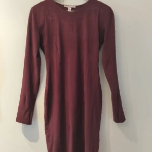 Vinröd tight klänning Nelly storlek M - Vinröd figursmickrande klänning från Nelly, tyget är i lätt mockaimitation. Storlek 38/M. Lite mörkare än vad det verkar på bilderna.