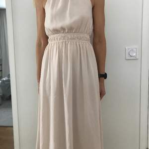 Jättefin klänning från H&M, ljusbeige Stl XS, passar en small. Polyester crepe. är i nyskick. Nypris 400:-