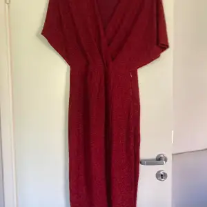 Oanvänd röd glittrig midi klänning strl 38 från Bubbleroom. Liten slits framtill och dold dragkedja i sidan. 