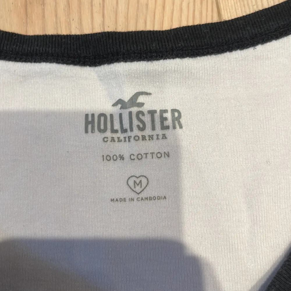 Vit t-shirt från Hollister med svarta detaljer. 100% bomull. Supersnygg o skön. Storlek M men liten i storleken, passar mig med XS o passar även S. Bra skick. OBS: ingen fläck, endast vattenstänk (bild 5). KOLLA MIN PROFIL💞. T-shirts.