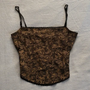 Brunt och svart linne med orm mönster - Fint linne med korsett uppbyggnad. Fint skick och mycket bekväm. Fin spets på botten och tyg på insidan för bysten. Axelbanden är justerbara. Skriv gärna till mig om du undrar något mer eller vill se ytterligare bilder!<3
