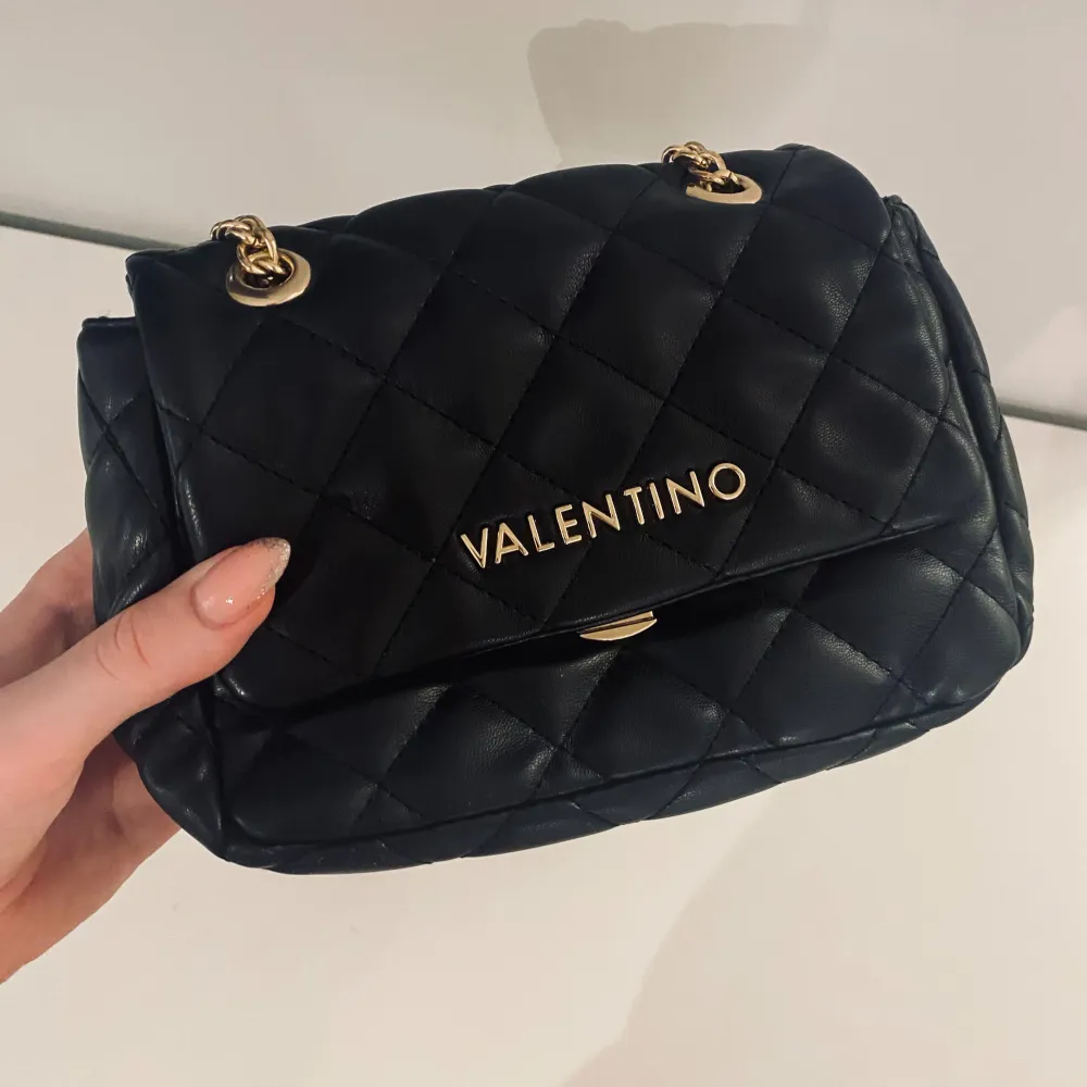 Svart väska från valentino bags. Det är den mindre modellen av Ocarina. Jag har aldrig använt den men har lånat ut den en gång. Använder endast större handväskor så därför säljer jag den. Väskan är i perfekt skick och har inga slitningar eller skador. Accessoarer.