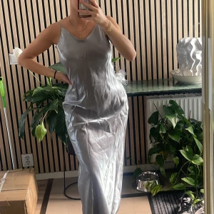 Klänning - Silvrig klänning. En gammal silvrig klänning som man sytt in lite inifrån därav lite lösa sömmar. Inte stretchig. Står att det är en storlek M men eftersom den är insydd så skulle jag säga att det är en S