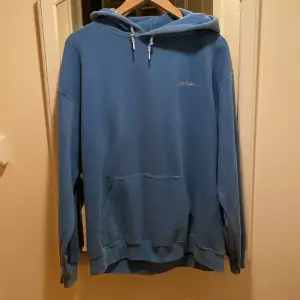 Blå hoodie med ett liten broderad text