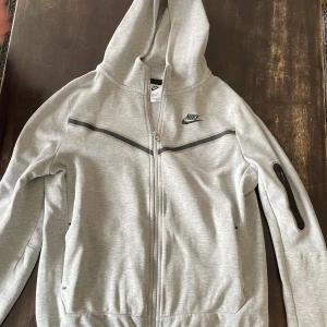 Nike tech flecce grå - Den är i okej skick, ett litet hål på ärmen och nopprig annars e allt bra.