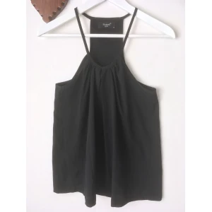 Linne i matt satin, stl XS, svart, stilrent, enkelt - Ett stilrent linne från Sisters Point. Matt satin med rynkad detalj fram. Mycket lätt noppig på ena sidan. Mått i cm: bröstvidd 63; längd fram från axeln 63.