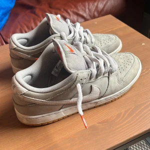 Nike dunk sb low - Ljus gråa Nike dunk sb low bra skick. Inga defekter förutom att dom bara är lite allmänt slitna. Priset är inte fast.