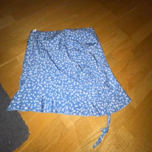 Kjol - Säljer en blå kjol med vita små blommor på, köpt på Shein för 100kr säljer för 65kr för jag har aldrig använt den, lite liten i sin storlek!!