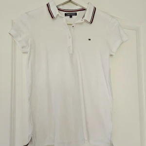 Vit pikétröja från Tommy Hilfiger  - Vit, stilren pikétröja från Tommy Hilfiger! Fina detaljer i kragen och snygg passform. Fint skick 🥰