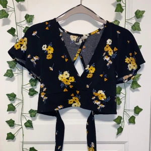 Blommig topp - En fin blommig topp med snörning från H&M i storlek XS. Toppen är i fint skick.