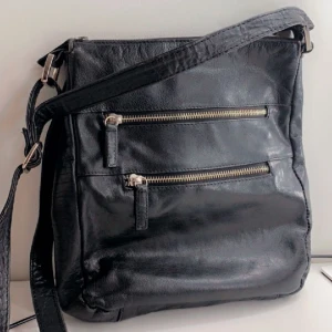 Svart Skinn Väska  - Fin svart skinnväska! Helt oanvänd! Rymlig och i bra kvalitet! Axelband! Flera fickor! Säljer då jag inte har användning för den längre 💕Pris kan såklart diskuteras☺️ 