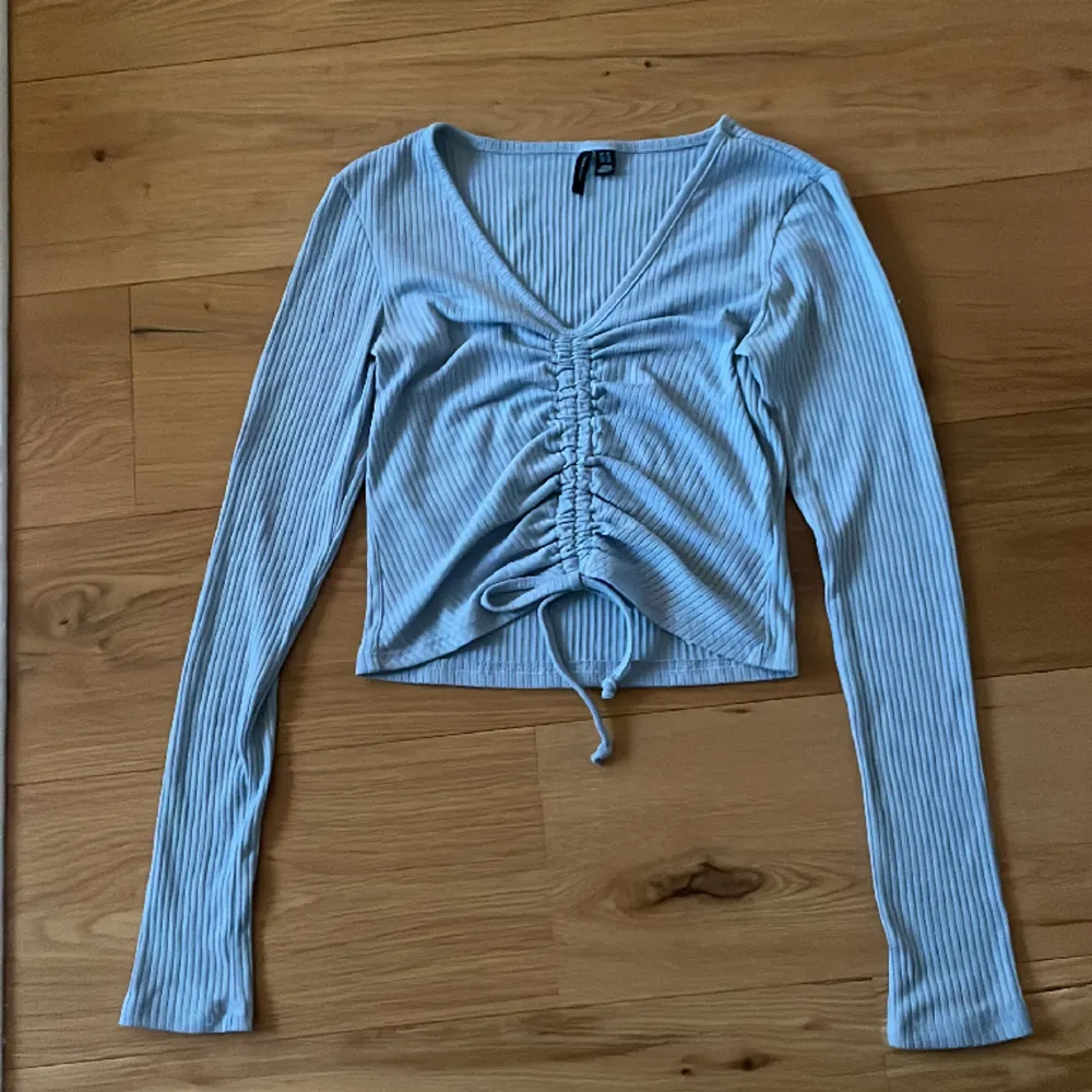 Ljusblå ribbad långärmad tröja i storleken XS. Köpt på Vero Moda och är i mycket bra skick. (Går att dra ihop snörena så tröjan blir kortare). Tröjor & Koftor.