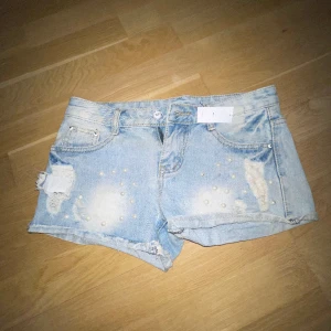 Lågmidjade shorts - Snygga lågmidjade shorts med slitningar och pärlor. Köpta i Thailand. Det står M på lappen men skulle säga att det är storlek Xxs eller Xs. Använd gärna köp nu knappen