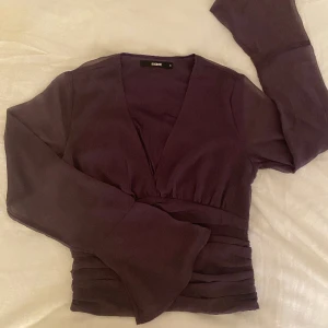 Lila blus - Långärmad blus som har ett genomskinligt tyg (ish) på armarna som även är utsvängda. Formar kroppen fint.