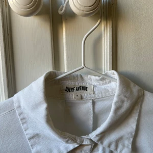 DJERF AVENUE BREEZY SKJORTA  - Vit skjorta från Djerf Avenue. I mycket fint skick, stl S. Väl omhändertagen och skjortan har en superfin kvalité. Säljer endast pga jag föredrar mer oversized modell. Denna är normal i storlek men lite bredare då det är en boxig modell. 