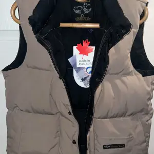 Canada Goose Vest Beige colour size Women’s Small. Used but in very nice condition! All original tags are still on. Inside number proof. Inside tag. Black interior. Real goose down. Very warm. 