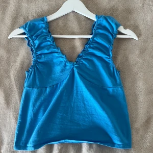 2000-tals inspirerad blå topp  - Blå topp med räfflade ärmar från Urban outfitters som endast är använd några fåtal gånger. Väldigt bra skick och fin passform. Något mindre i storleken, skulle säga att den sitter som en S/M. Priset kan diskuteras vid snabb affär. 