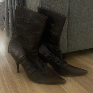 Stövlar med klack  - Bruna / röda stövlar med klack. Dragkedja bak på skorna, och dom är inte varma