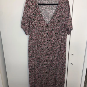 Sommarklänning  - Blommig rak sommarklänning i storlek xl.  Knappar hela vägen fram och en band i ryggen för att kunna markera midjan så som man vill ha den.