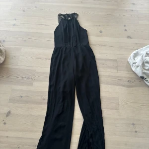 svart jumpsuit med öppen spetsrygg - Fin jumpsuit, saknas dock en knapp. Se bild 