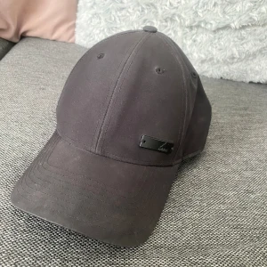 Adidas keps - Säljer en svart adidas keps med deras märke på en svart metallbit på högersidan där fram🤩Justerbar så passar alla storlekar!! I ett bra skick🙌🏻Billiga kläder➡️min profil😚