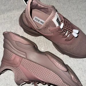 Bruna sneakers från Steve Madden - Anvädna en gång, etikett kvar undersida sko. Ett par bruna sneakers från Steve Madden med snörning och en robust sula. Skorna har en stickad ovandel och är designade för komfort och stil.
