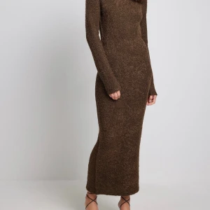 Brun långärmad klänning med öppen rygg - En elegant brun långärmad klänning med en åtsittande passform. Klänningen har en öppen rygg som ger en sofistikerad och stilren look. Perfekt för höst- och vinterevenemang.