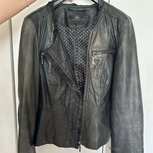 Kello scandinavia vintage svart skinnjacka - Kello scandinavia Svart skinnjacka med två fickor högt upp och en dragkedja så man kan stänga jackan såklart. Jackan är vintage och jätte snygg. På insidan är det som blommor mönster.